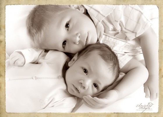 Newborn boy with brother high key studio portrait