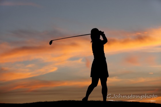 Lady taking a golf swing.