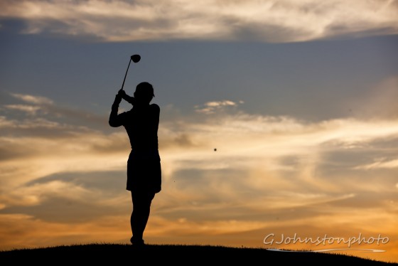 Lady hits a golf ball.